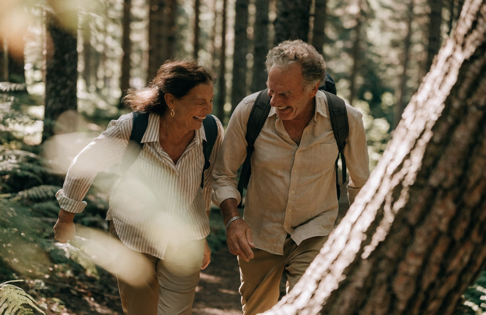 A couple in their sixties hiking and laughing together in a forest