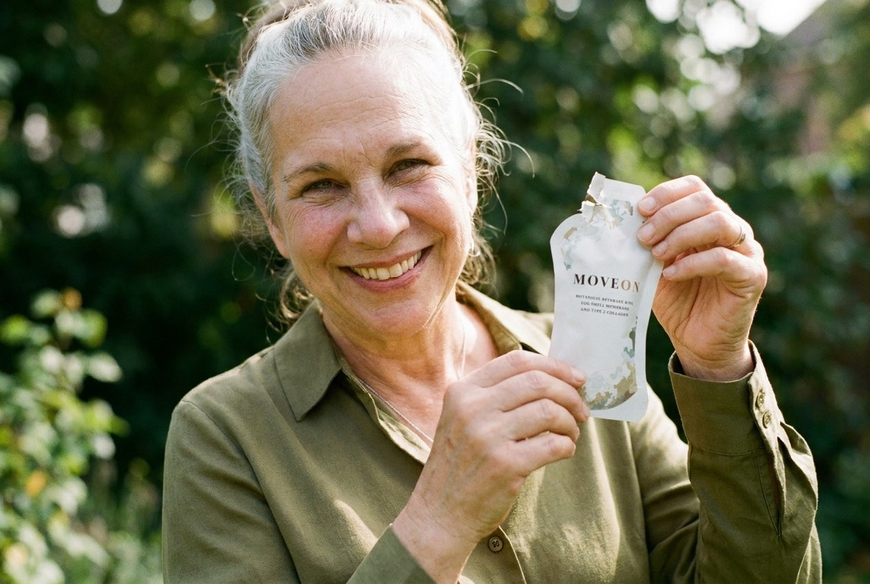 A woman in her sixties smiling and holding a MoveOn sachet in a garden